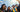 Group of five students in graduation gowns and caps with confetti around them