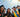 Group of five students in graduation gowns and caps with confetti around them