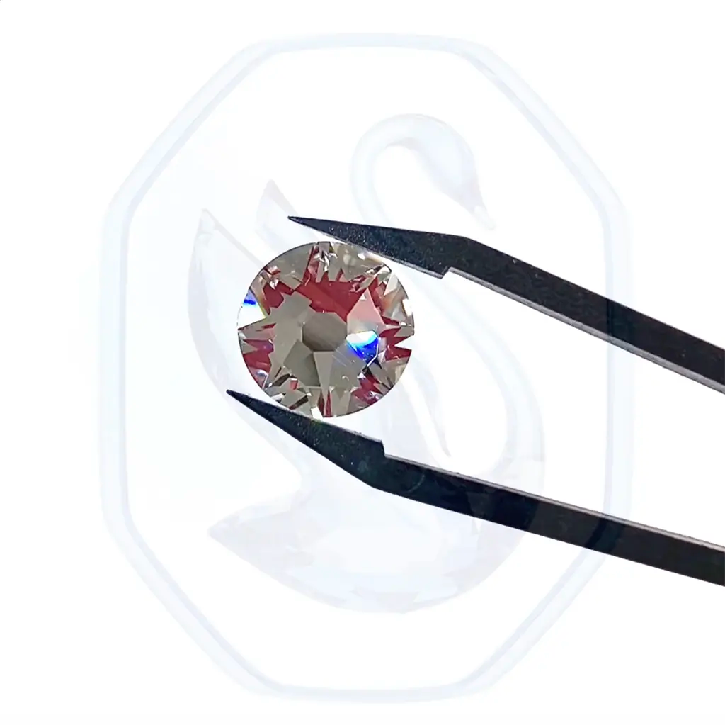 Swarovski flatback rhinestone held in tweezers being rotated with the Swarovski logo in the background